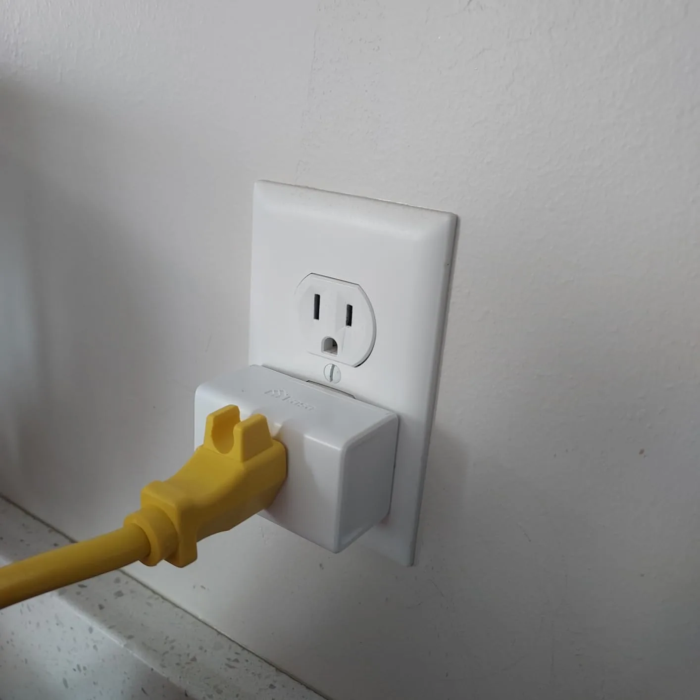 Customer photo of smart plug installed in wall outlet next to traditional switch