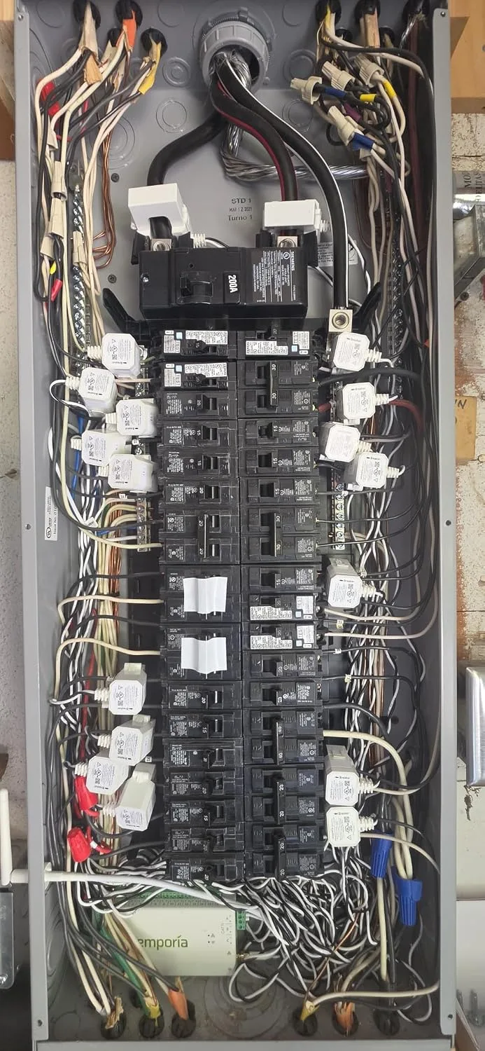 Customer photo of energy monitor display mounted on electrical panel showing real-time power consumption readings